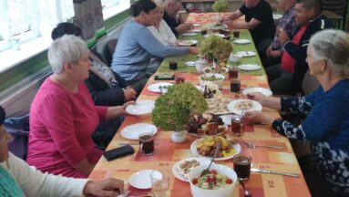 Osoby siedzą przy stole podczas posiłku