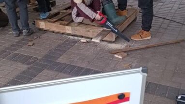 Na zdjęciu znajduje się młodzież w altanie. Z przodu widnieje plakat Działaj Lokalnie z logo Programu