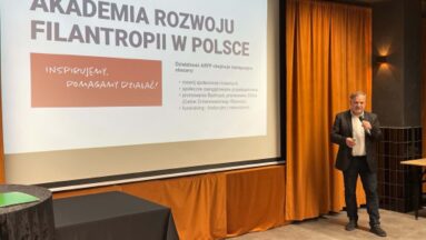 Na ekranie prezentacja i prowadzący.