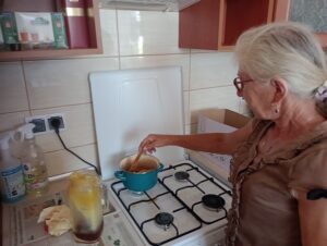 Uczestniczka warsztat&oacute;w podczas topienia naturalnego wosku pszczelego w garnku.