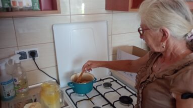 Uczestniczka warsztatów podczas topienia naturalnego wosku pszczelego w garnku.